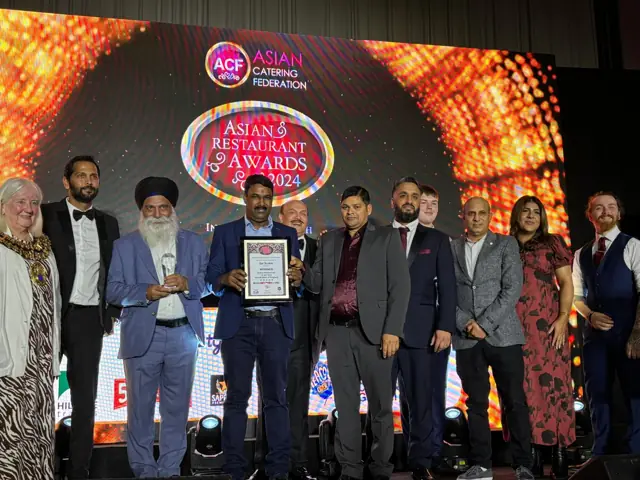 Winner of Indian Restaurant of the Year, North West, at the Asian Restaurant Awards 2024, holding the certificate on stage