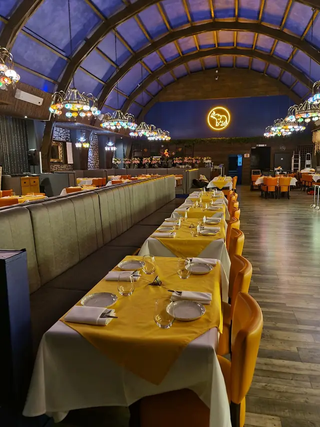 The Sai Surbhi dining hall with a vaulted ceiling and long tables laid with gold runners