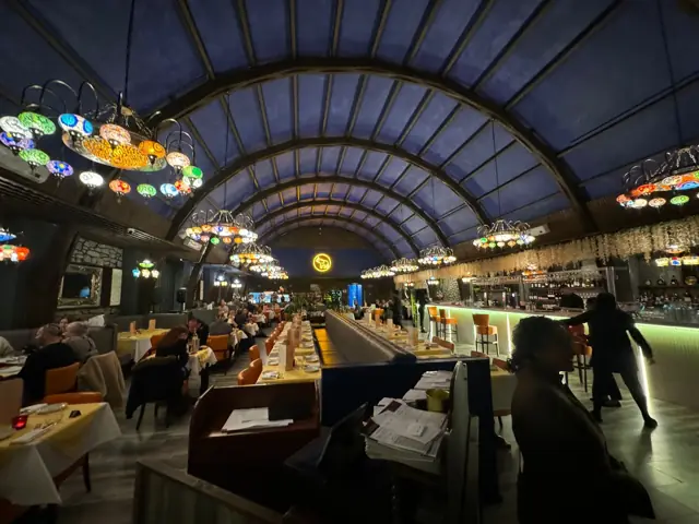The restaurant at night with the arched ceiling lit and guests at the tables
