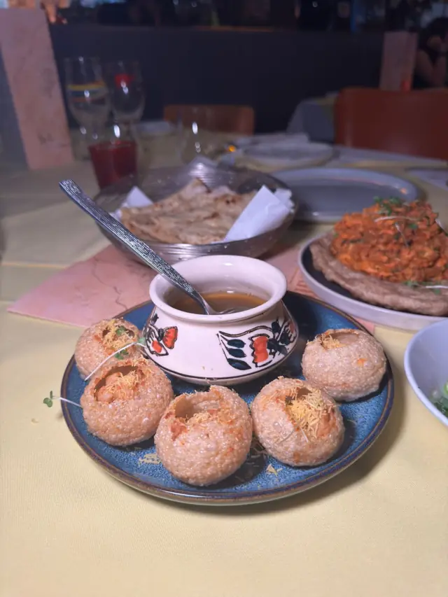 Crisp paani poori shells with a pot of spiced water