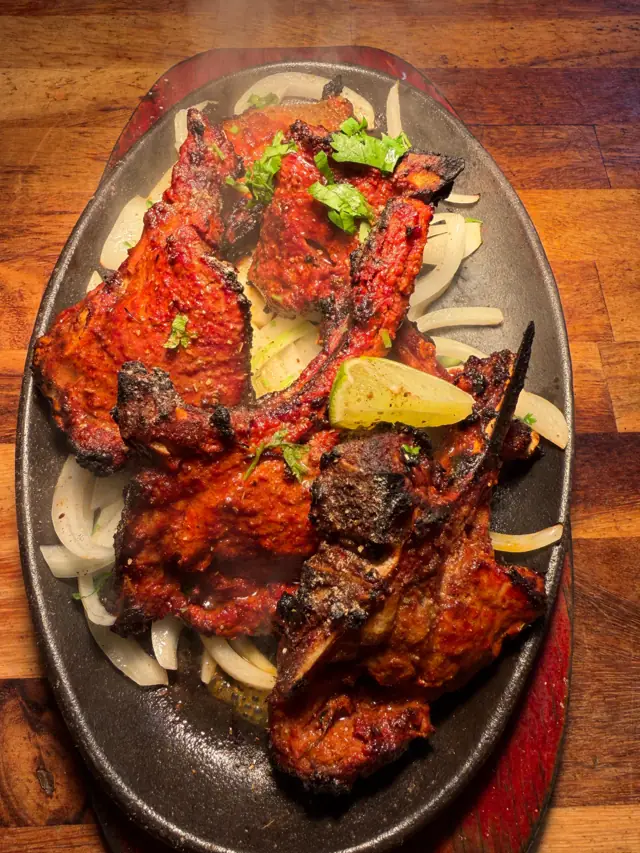 Tandoori chops and chicken on a sizzling plate with lemon and onions