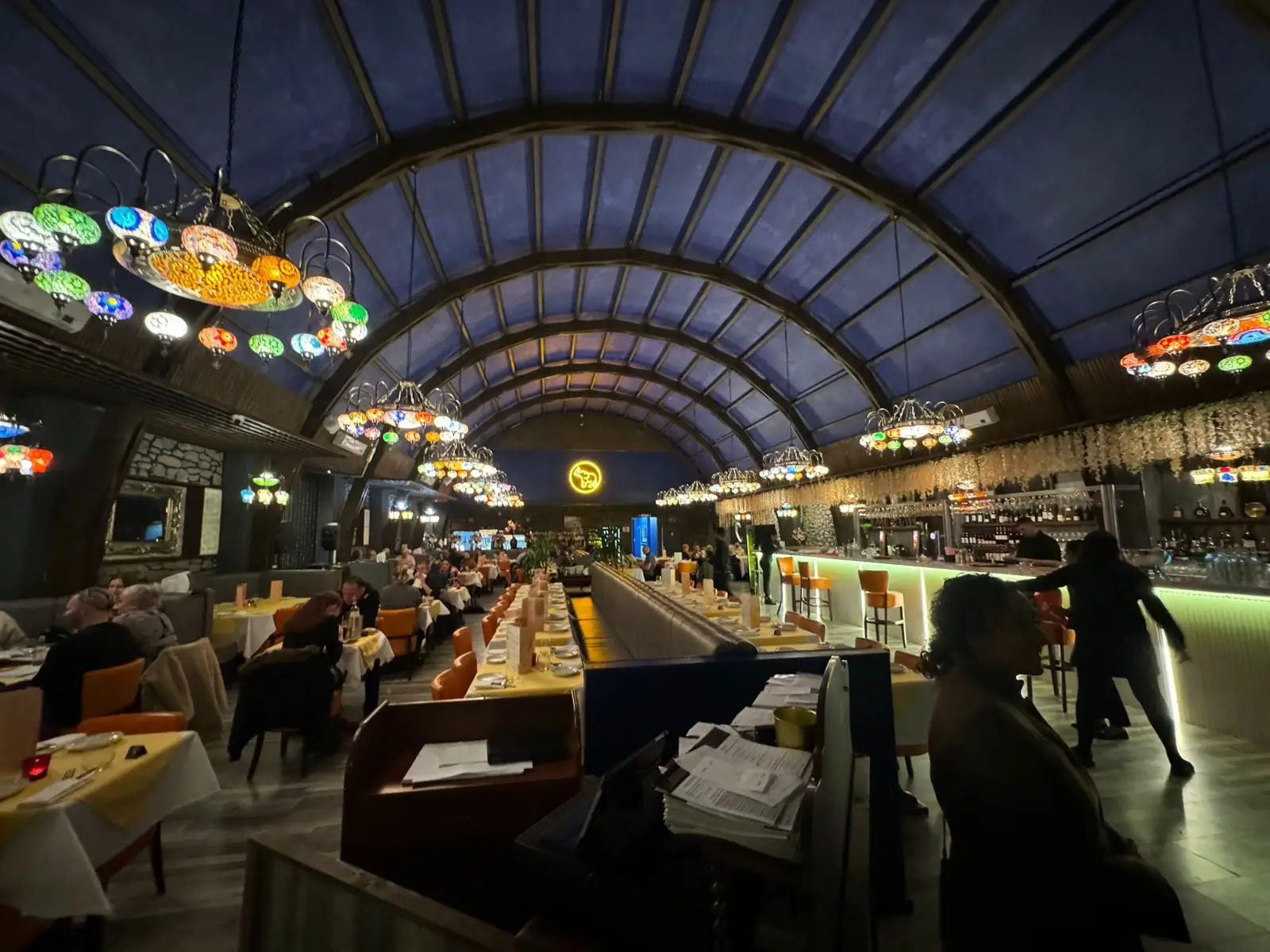 The restaurant at night with the arched ceiling lit and guests at the tables